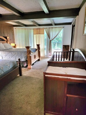 A bedroom with two beds, a wooden headboard, a canopy, and a view of the outdoors.