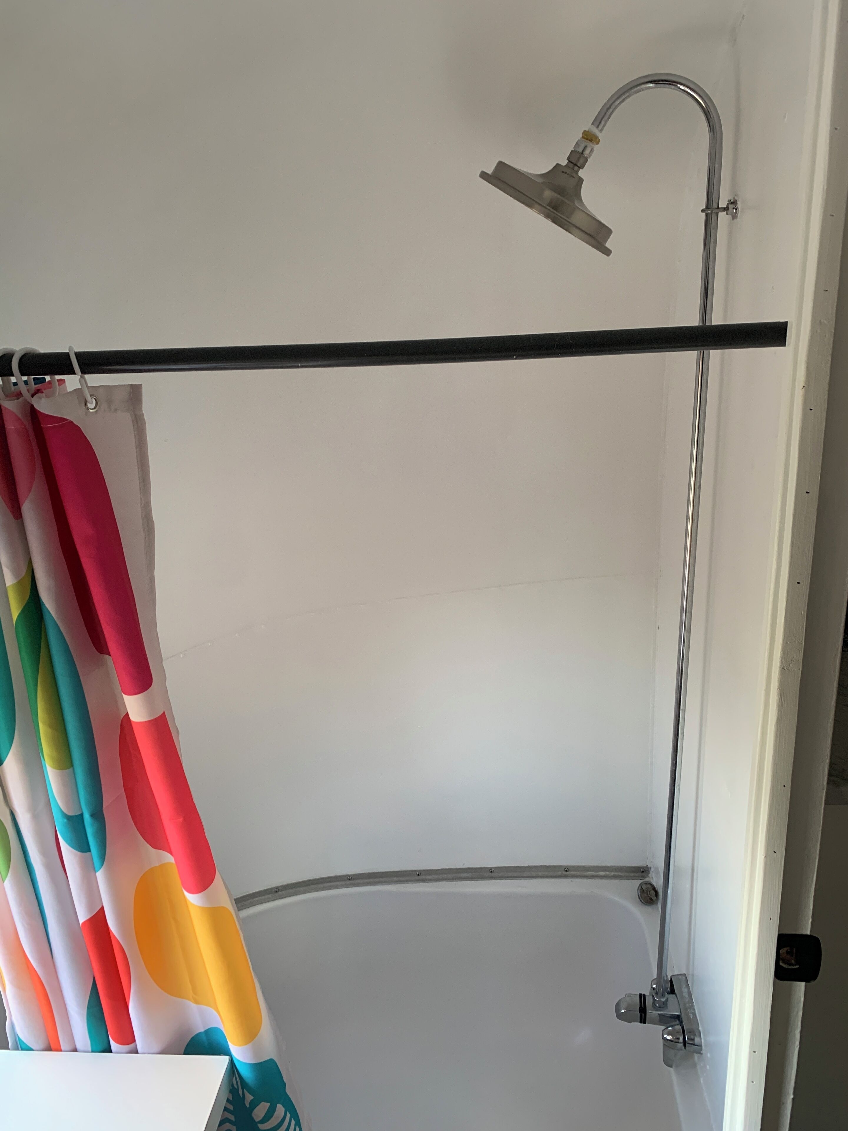 A bathroom with a shower, a bathtub, and a colorful shower curtain.