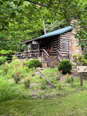 Eine Blockhütte mit Veranda, einem Schild mit der Aufschrift „1930“ und einem Schild für „Greenwood Historic Cabin“.
