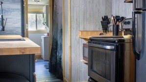 Eine kleine Küche mit Einbauofen, Kühlschrank und einer Holzarbeitsplatte.