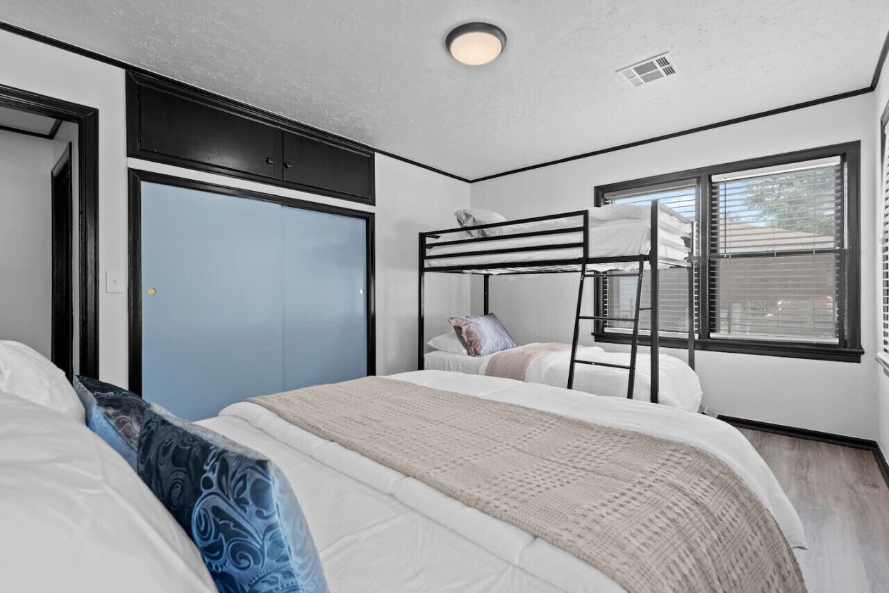 A bedroom with a bunk bed, a wardrobe, and a window with blinds.