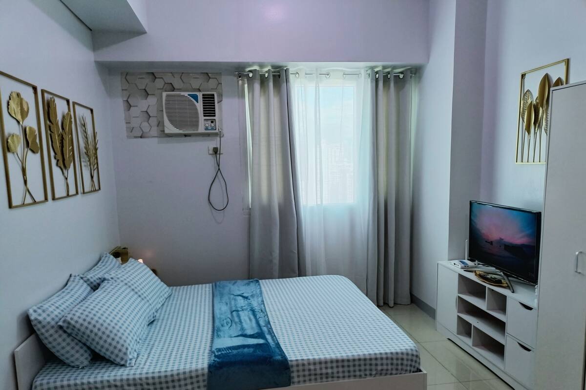 Ein Schlafzimmer mit einem Bett, einem Fernseher, einem Kleiderschrank und Wanddekoration.