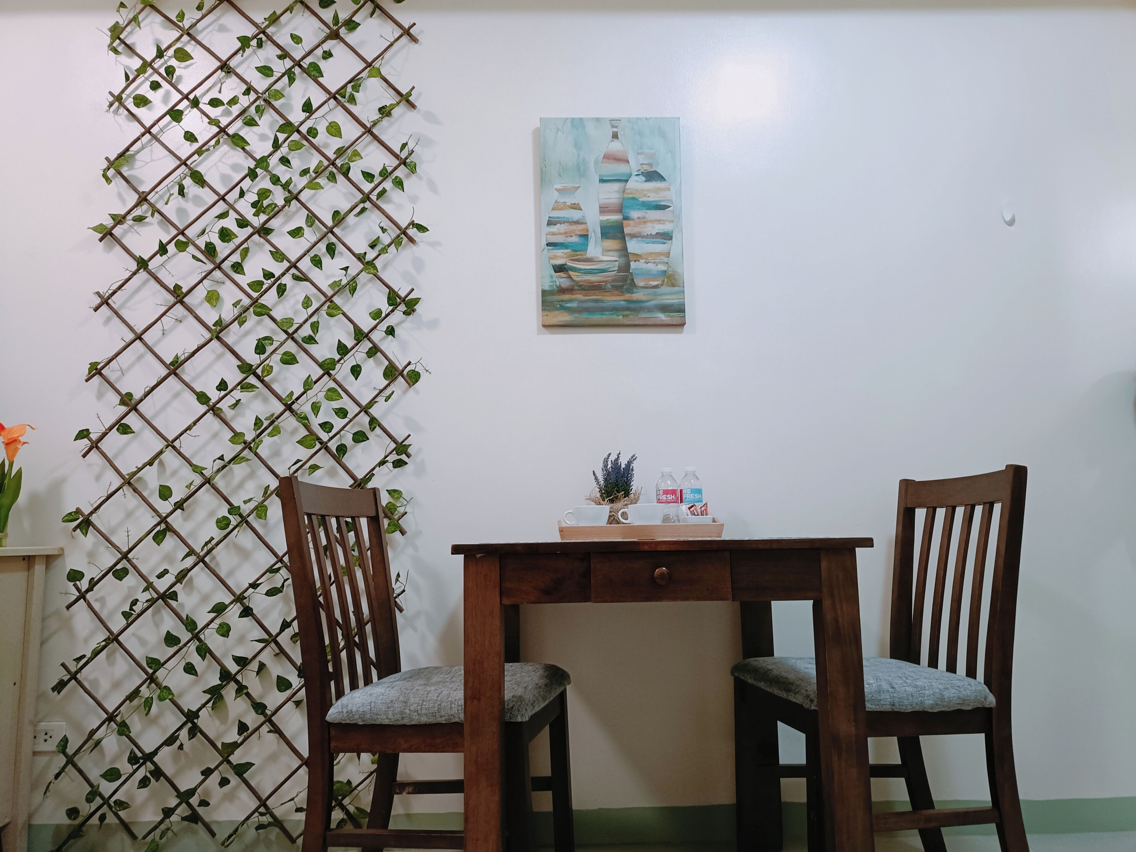 A dining area with two wooden chairs, a small table, and a decorative plant wall.