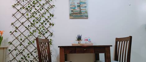 A dining area with two wooden chairs, a small table, and a decorative plant wall.