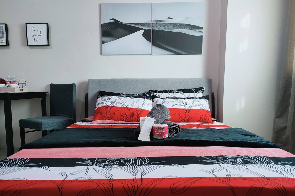 Ein ordentlich eingerichtetes Hotelzimmer mit einem Bett, einem Nachttisch und einem gerahmten Bild an der Wand.
