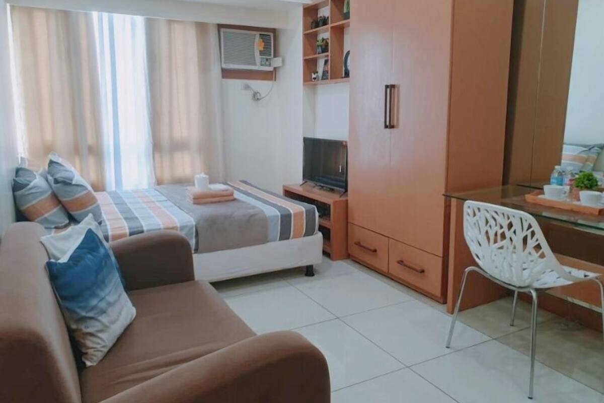 Ein modernes Schlafzimmer mit Bett, Fernseher, Schreibtisch und Kleiderschrank.