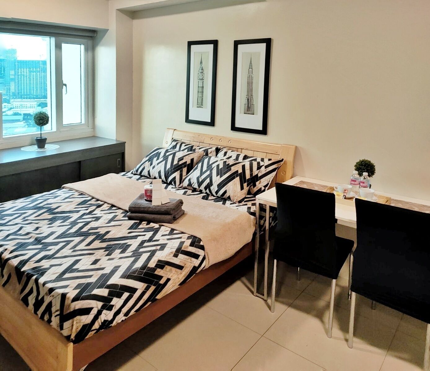 A modern bedroom with a bed, two framed pictures, a desk, and a chair.