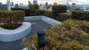 Een dakbostuin met uitzicht op een stadshemelbeeld, met moderne gebouwen en een heldere lucht.