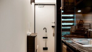 A compact kitchen with a sink, a small countertop, and a door leading to a bathroom. - 2023 Open/Shinjuku Okubo/5min 2 JR/Premium Capsule (Shinjuku City)