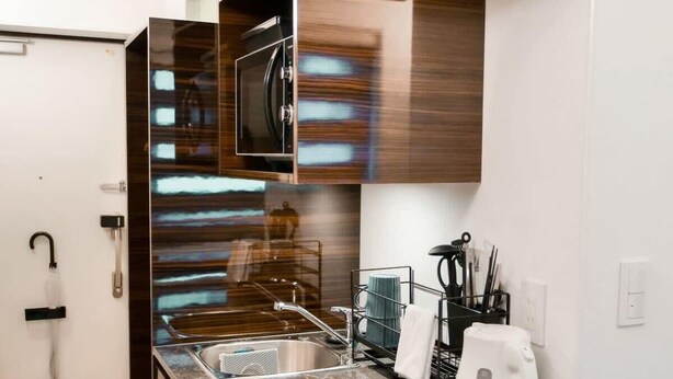 A modern kitchen with a built-in microwave, a sink, and a kettle on the countertop. - 2023 Open/Shinjuku Okubo/5min 2 JR/Premium Capsule (Shinjuku City)
