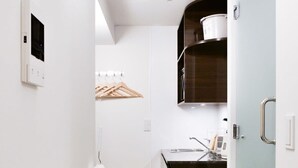 Una cocina compacta con armarios blancos, encimera oscura y puerta azul claro.