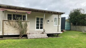 Une maison de plain-pied avec un porche à l’avant, un petit jardin et une clôture en bois.