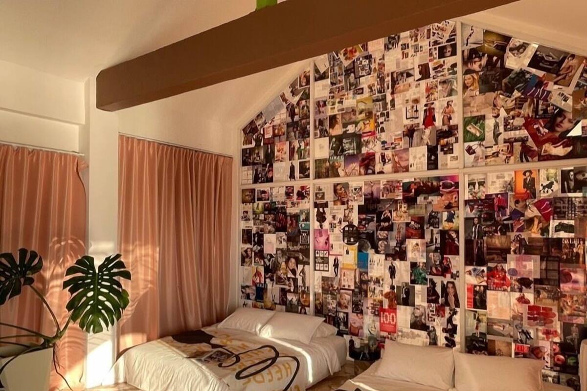 A bedroom with a wall covered in photos and a bed with white bedding.