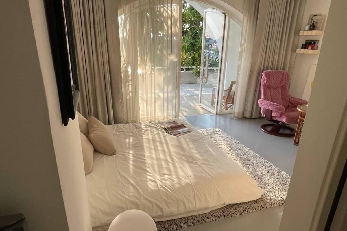 A bedroom with a large bed, a chair, and a view of the outdoors.