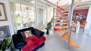A modern interior with a spiral staircase, a red sofa, and a dining area with wooden chairs. - CASA PAPA Home&Space (Nakhon Chai Si)