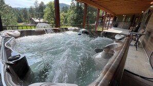 Una vasca idromassaggio con un pontile in legno e vista su una zona boschiva.