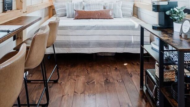 A cozy room with a bed, a desk, chairs, and a bookshelf. - Tiny Timber- Stunning Tiny House (Spearfish)