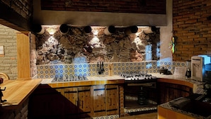 Uma cozinha com painel de backsplash de pedra, backsplash revestido de azulejos e bancada de madeira.
