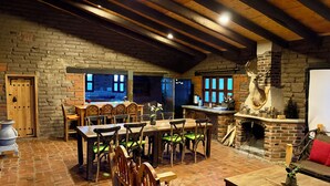 Uma área de jantar rústica com paredes de tijolo, vigas de madeira e lareira de pedra.
