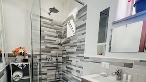 A modern bathroom with a glass-enclosed shower, a vanity with a mirror, and a tiled backsplash.
