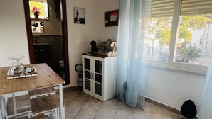 A small, tidy room with a wooden table, a cabinet, and a window with curtains.