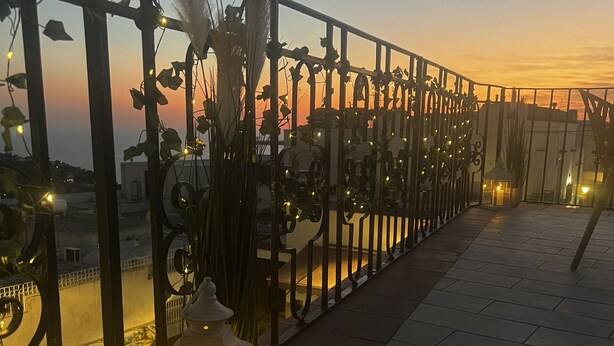 A balcony with a metal railing, decorative lights, and a lantern.