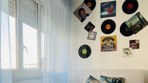 A room with a bed, a window with curtains, and a wall decorated with vinyl records.