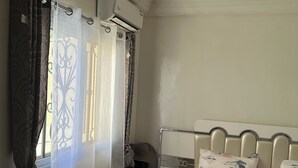 Ein Schlafzimmer mit einem Bett, einem Nachttisch, einem Spiegel und einer Klimaanlage.