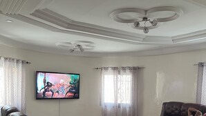 Ein Wohnzimmer mit Flachbildfernseher, Ledersofas, einem Glastisch und einem gemusterten Teppich.