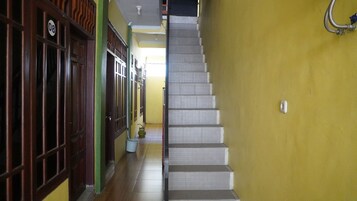 Una escalera con una pared amarilla y puertas de madera a la izquierda.