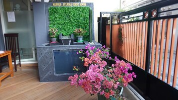 Una recepción con pared verde, plantas en macetas y un cartel que dice "NADYAH - ZULFINA GUEST HOUSE".