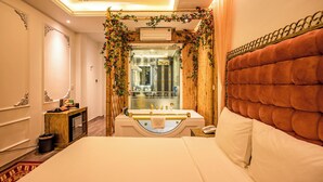 A hotel room with a large bed, a bathroom with a bathtub, and a wooden wall. - Mai Hotel  (Hanoi)