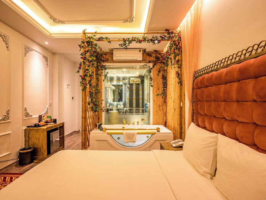 A hotel room with a large bed, a bathroom with a bathtub, and a wooden wall.