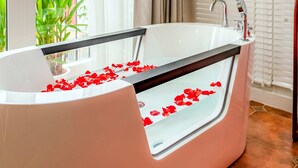 A modern bathroom with a large bathtub, a glass-enclosed shower, and a view of greenery outside. - Mai Hotel  (Hanoi)