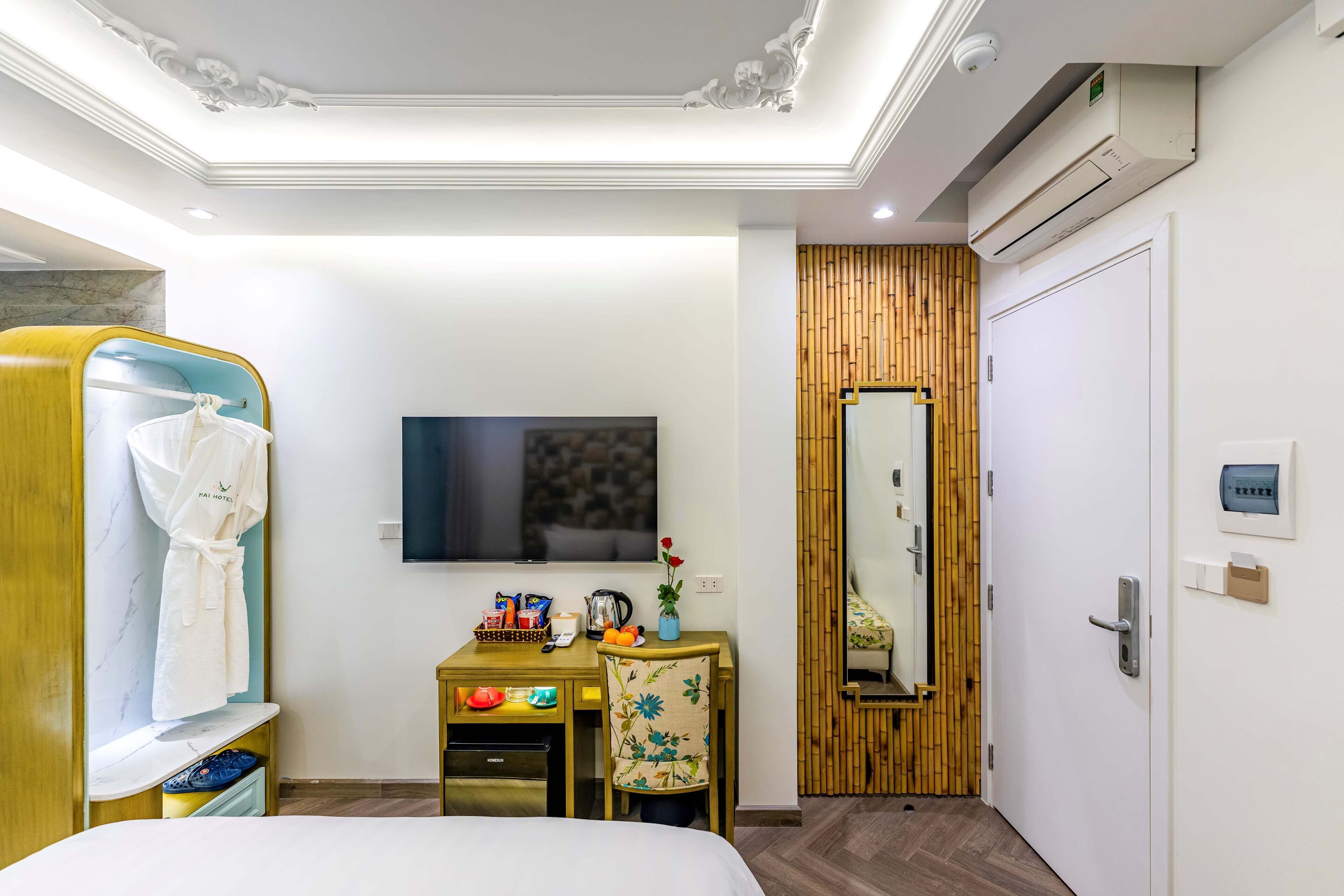 Habitación de hotel con cama, escritorio con silla, televisión, armario y aire acondicionado.