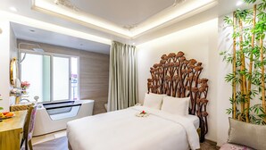 A modern hotel room with a large bed, a bathroom with a bathtub, a dining area, and a decorative wall with bamboo and flowers. - Mai Hotel  (Hanoi)