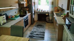 Eine kleine Küche mit Holzausstattung, einem Herd, einem Spülbecken und einem Fenster mit Vorhängen.