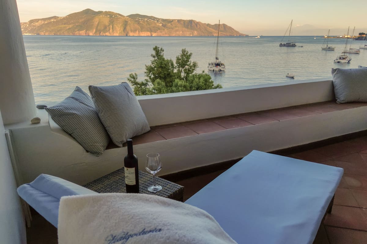 Balkon med havudsigt, vinflaske og et glas på et bord.