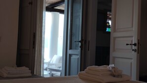 Quarto de hotel com uma cama, um banheiro visível através de uma porta aberta e uma pequena mesa com toalhas.