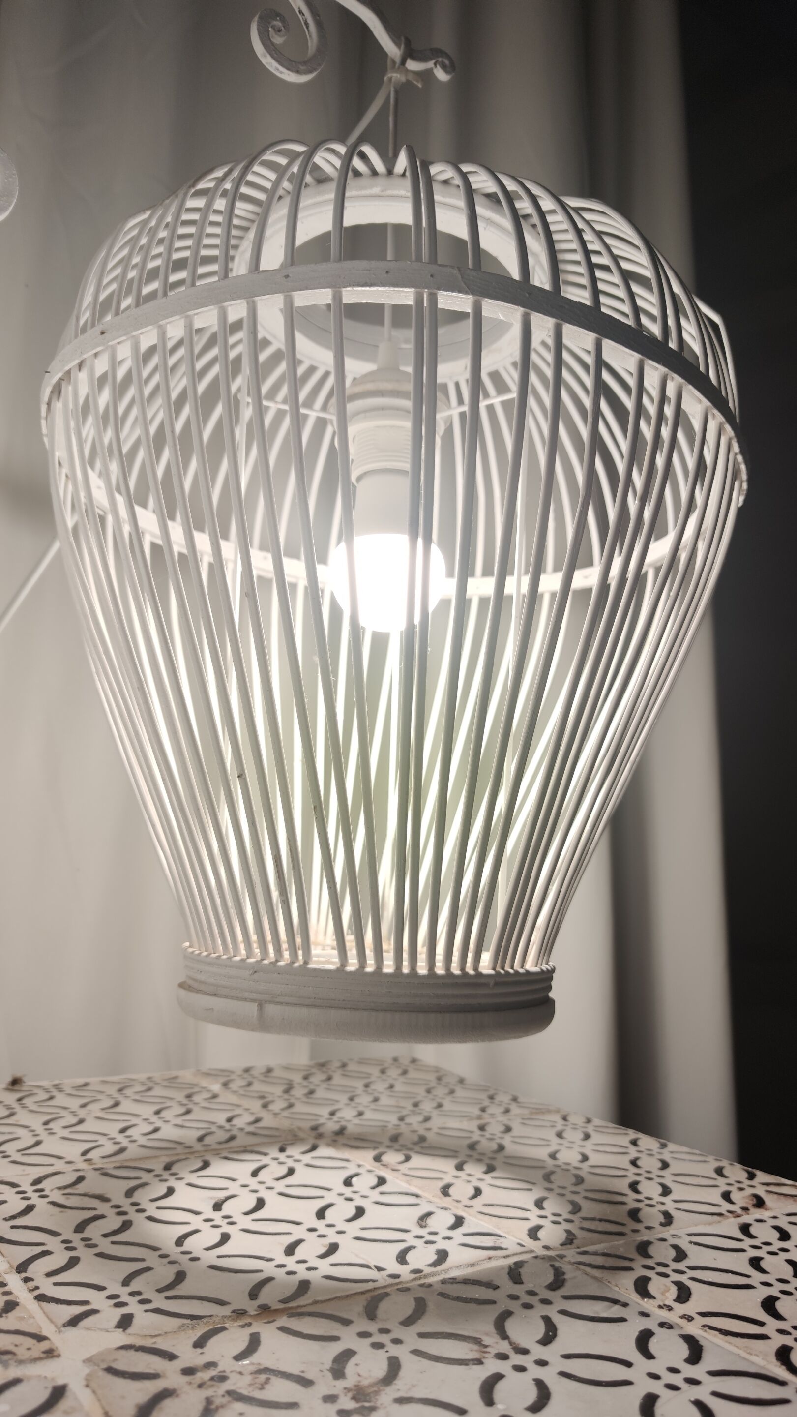 A white, ribbed, spherical lamp with a visible light source inside, placed on a patterned surface.