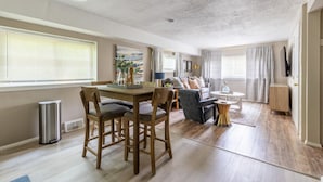 Un grand espace de vie comprenant une table à manger, des chaises, un canapé et un téléviseur.