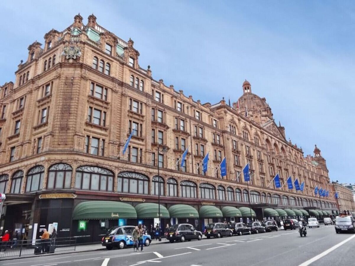 Um edifício grande e histórico com várias bandeiras, uma cúpula imponente e uma série de arcos.