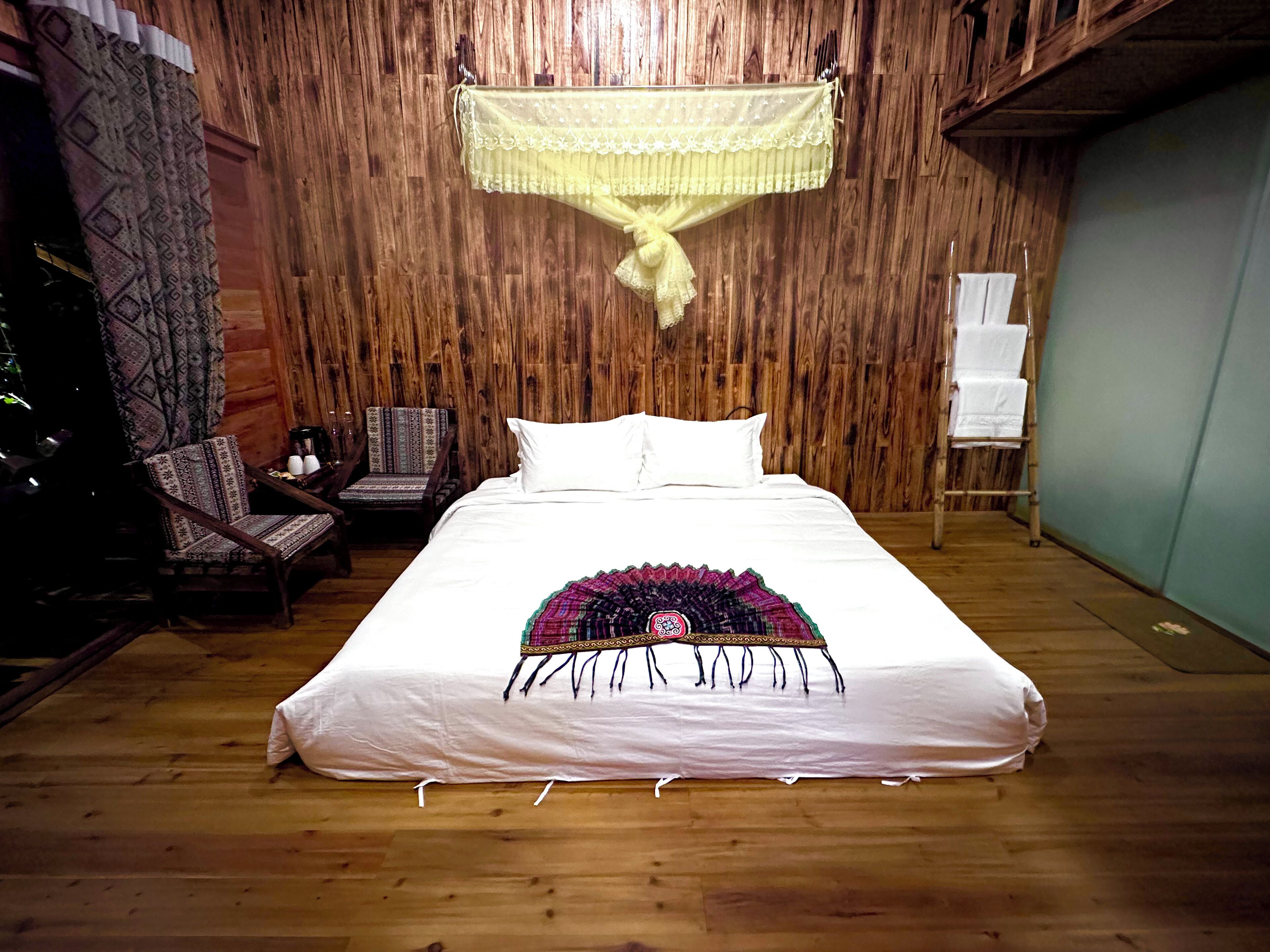 Um quarto com painéis de madeira, uma cama, uma cadeira e uma pequena mesa.