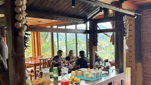 Un rústico espacio de bar con barra de madera y un amplio ventanal con vistas a un paisaje montañoso.
