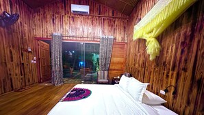 Una habitación con paneles de madera, una cama, una mesita de noche y un ventanal con cortinas.