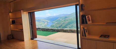 A room with a large sliding glass door leading to a scenic outdoor view of a valley and river.