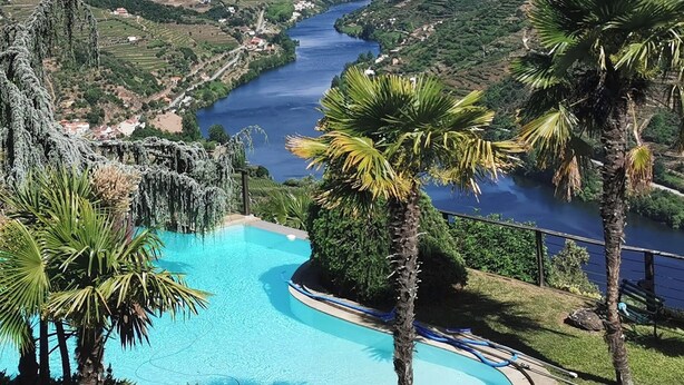 A pool with a view of a river and surrounding greenery.