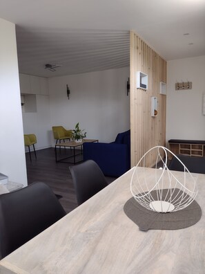 A modern dining area with a wooden table, black chairs, and a blue sofa.