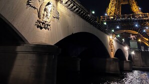 Un pont avec une grande tour illuminée en arrière-plan.