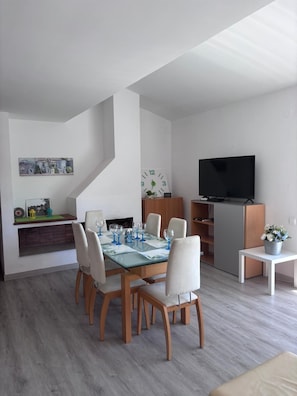 Un salon moderne comprenant un coin repas, un téléviseur à écran plat et un escalier.